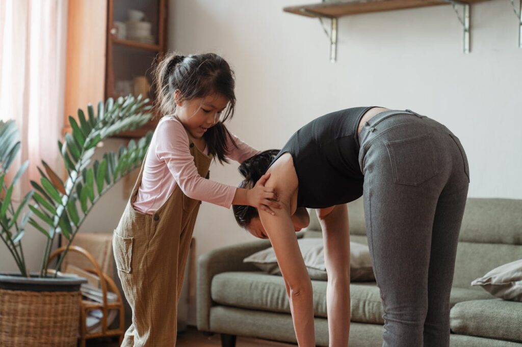 Young flexible ethnic woman with cute daughter during workout together